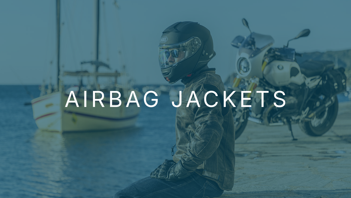 Rider in a Helite airbag jacket and helmet beside a motorcycle at a harbour