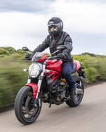 Rider on a red naked motorcycle wearing the black Roadster leather airbag jacket