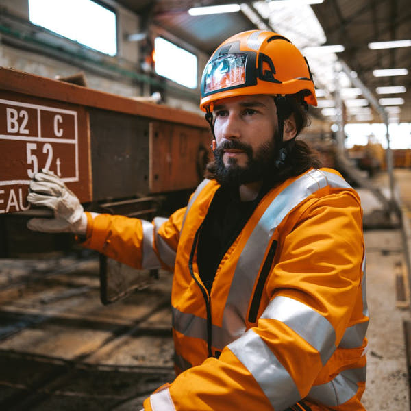 Industrial worker in a hard hat wearing a Helite AirFall high-vis jacket
