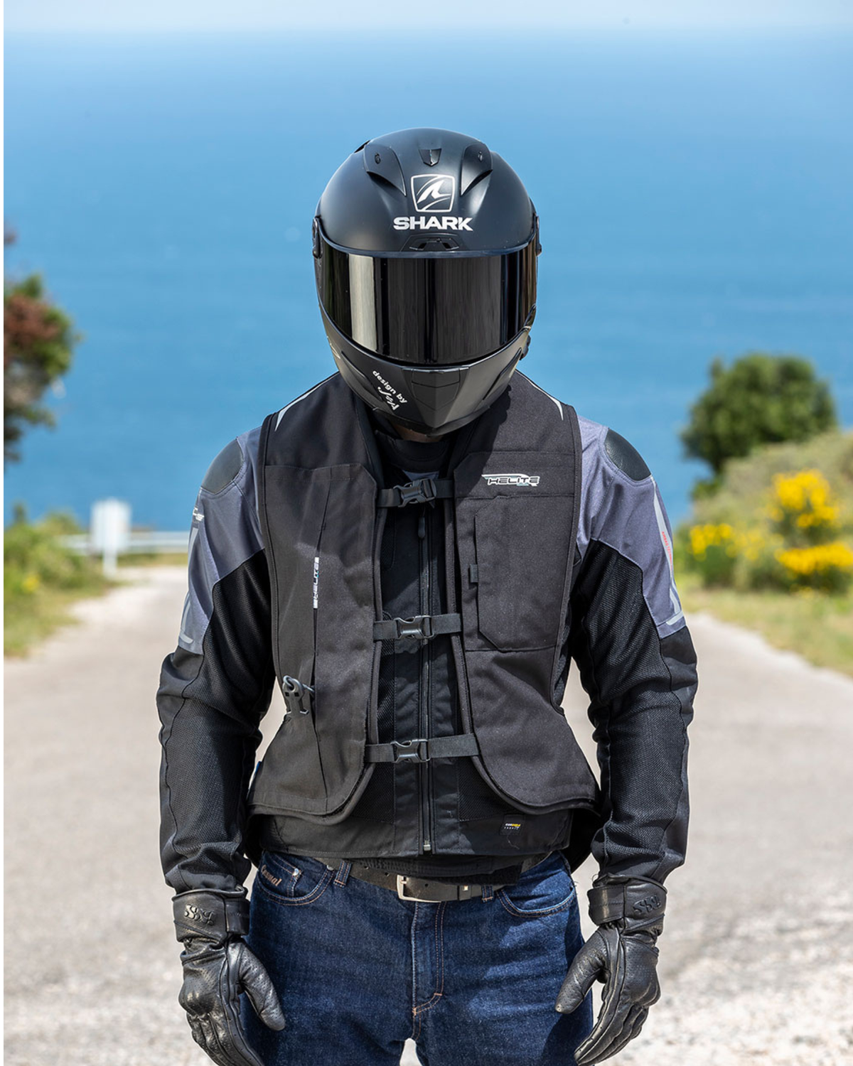 Motorcyclist on a coastal road wearing the black Turtle 2 airbag vest over a riding jacket