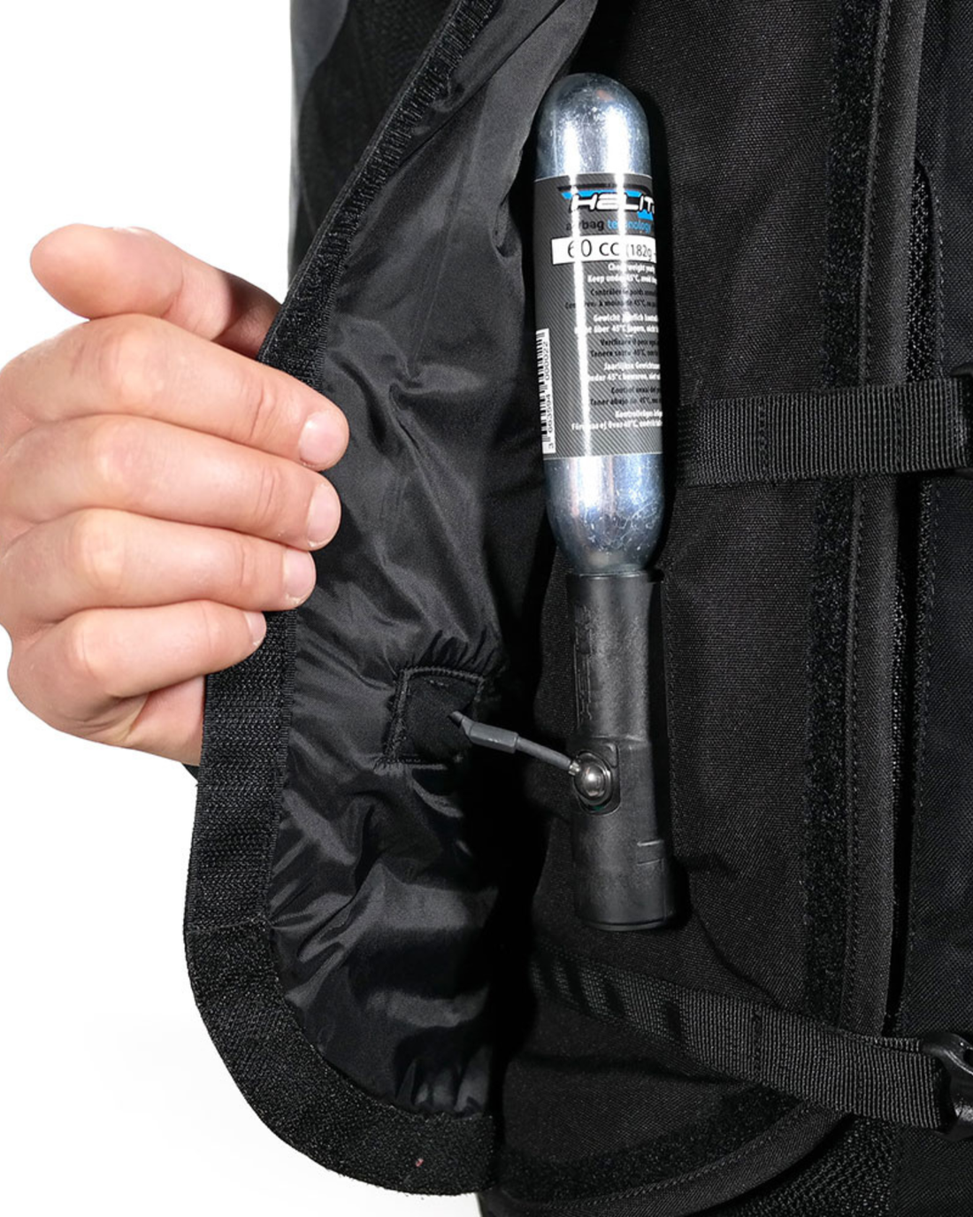 Hand fitting a CO2 cartridge into the pocket of the black Turtle 2 airbag vest