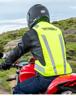 Motorcyclist riding a red bike seen from behind in the high-vis e-Turtle airbag vest