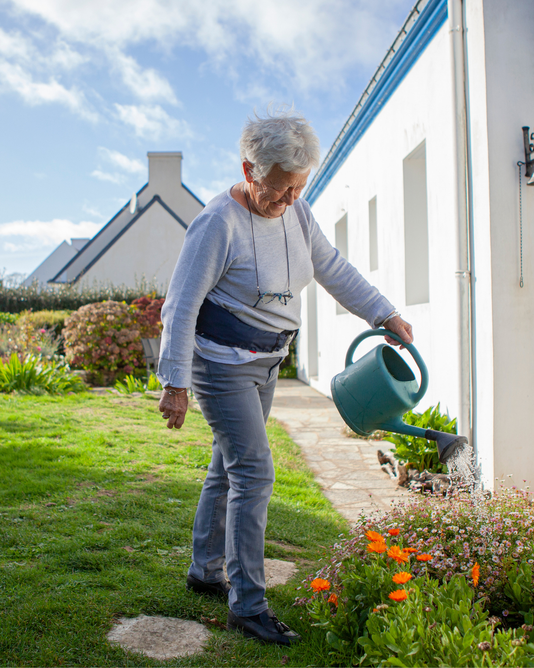 Older woman watering the garden while wearing the Helite Hip'Guard airbag belt